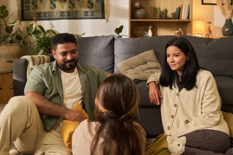 Portrait of family gathering in cozy living room. Parents engaging with child while sitting on floor with various decor elements around, creating warm and inviting atmosphere