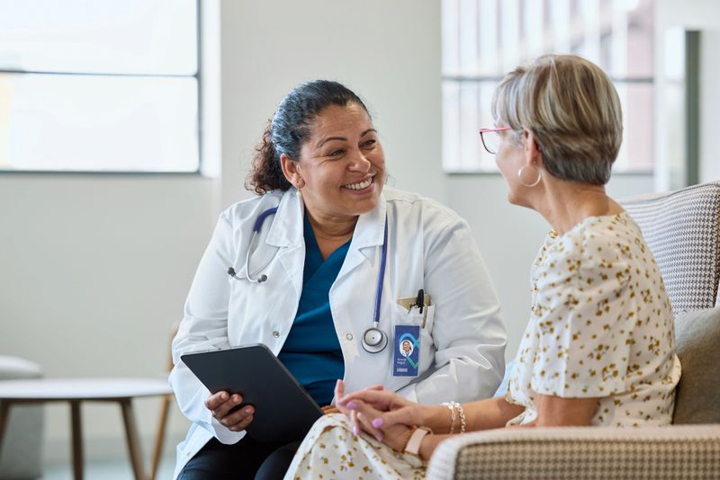 Smiling female physician sharing good news with senior woman at hospital. Doctor is consulting elderly patient. They seems to be happy.