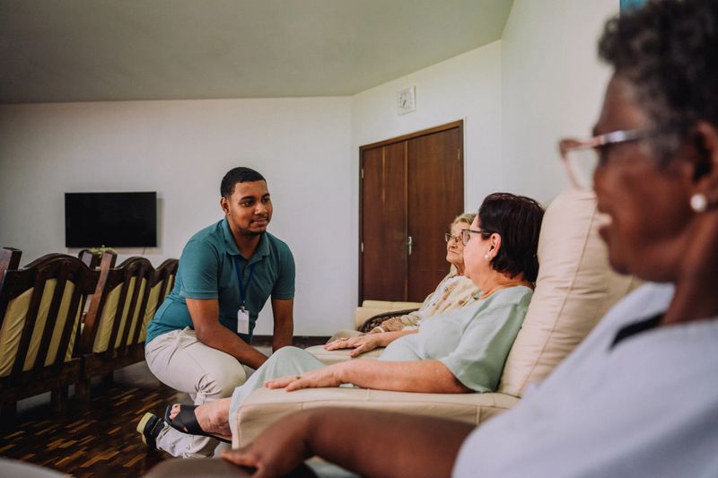 Young volunteer talking to elderly women in nursing home