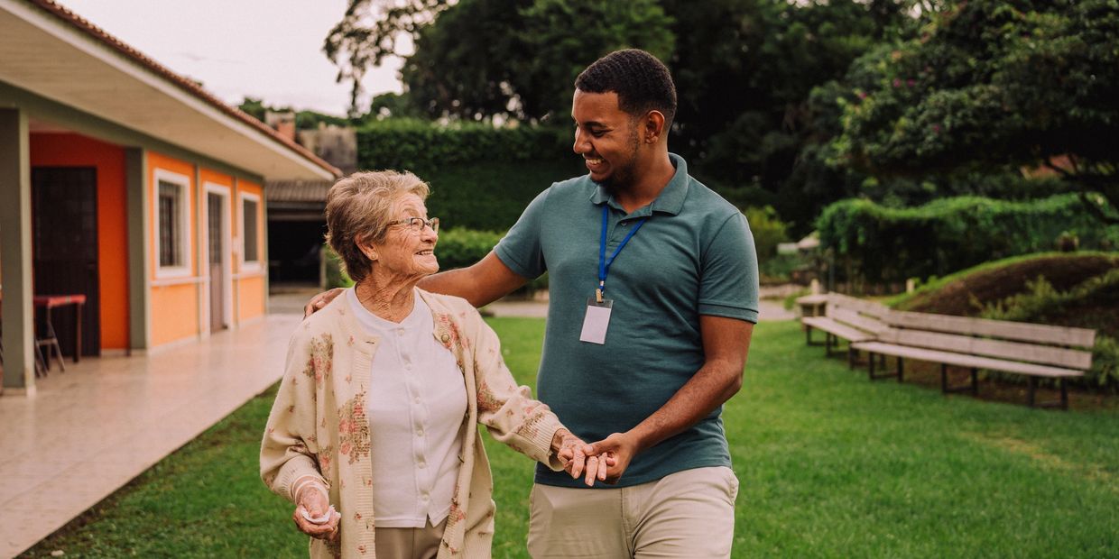 A young man and elderly woman share a joyful moment outdoors.
