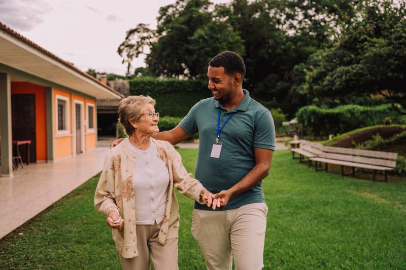 Volunteer walking in garden with elderly woman in nursing home
