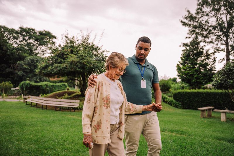Volunteer walking in garden with elderly woman in nursing home