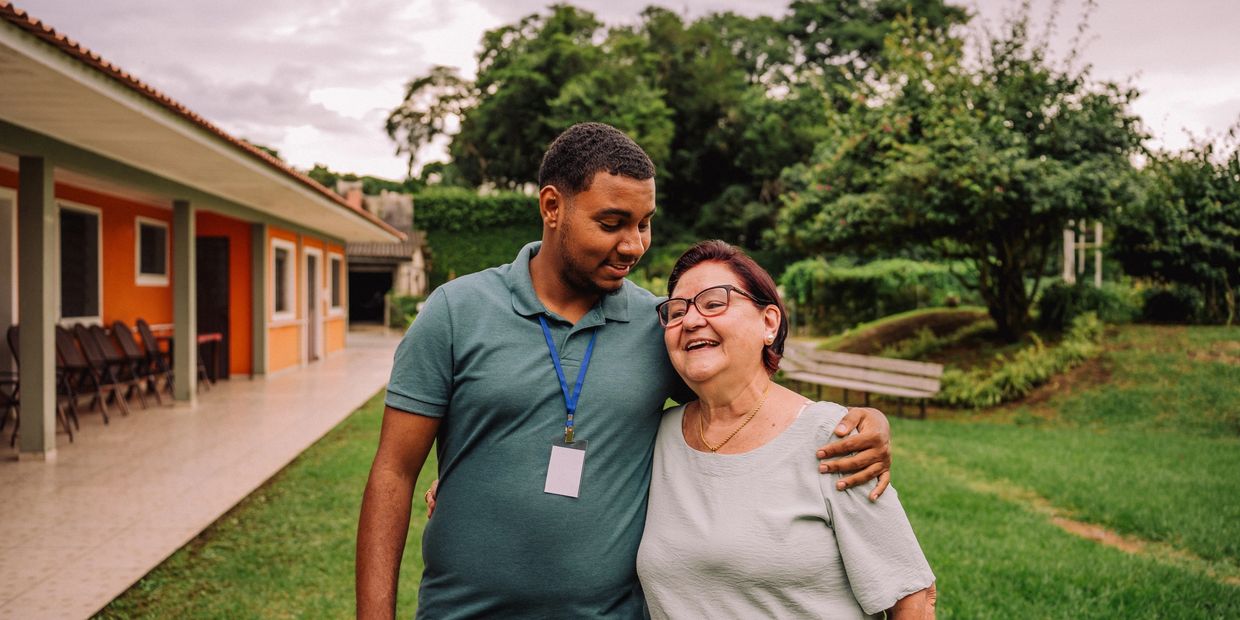 DSP with teal shirt side hugs and smiles at a woman in a gray shirt with eyeglasses.
