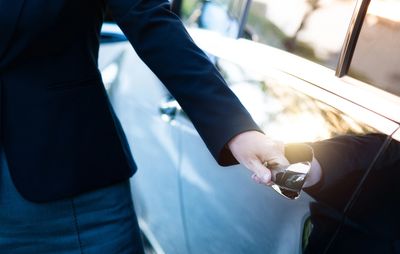 Person opening car door with keys in hand.