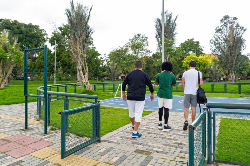 An adult man walks alongside two young men on their way to the park, ready to exercise. Between laughter and conversation, they demonstrate that staying active is a habit for all ages.