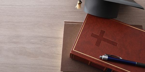 Graduation cap on a Bible with a pen.