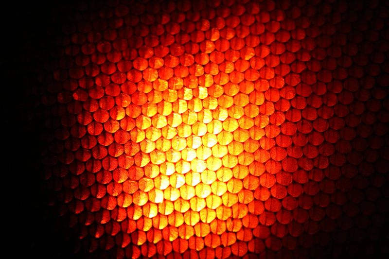Closeup view of a vibrant orange honeycomb pattern radiating warmth and light. The textured design creates an eye-catching abstract background suitable for various creative projects.