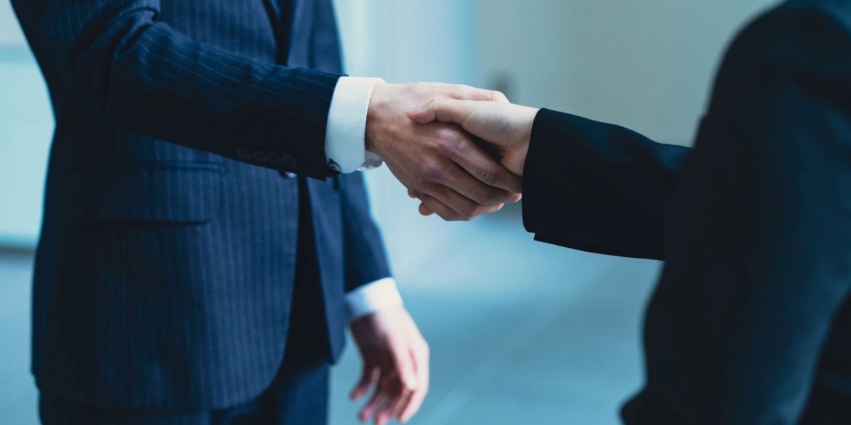 Two business professionals shaking hands in formal attire.