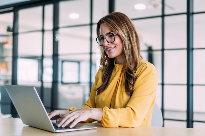 Elegant businesswoman sitting in her office and using laptop.