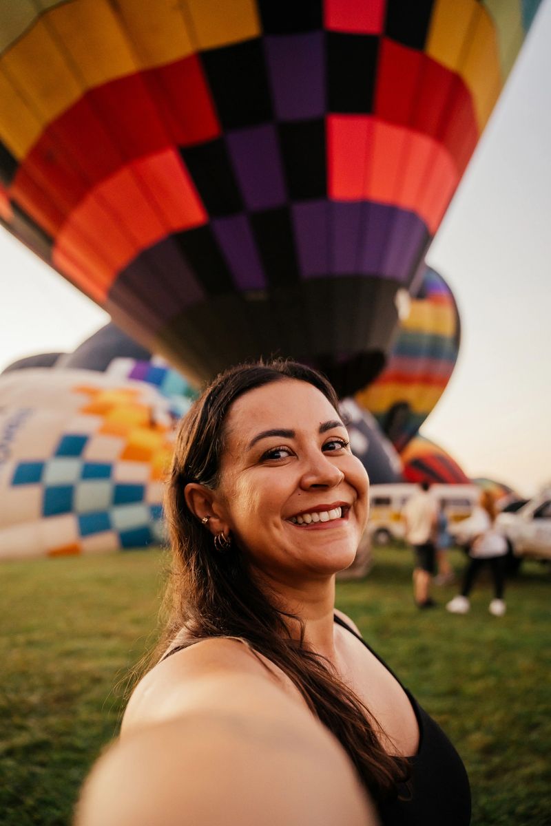 Latina woman taking selfie in front of a hot air balloon.