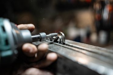 Close-up of a hand using a tool on a metal piece.