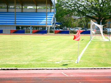 Empty soccer field corner with a red flag and goalpost.