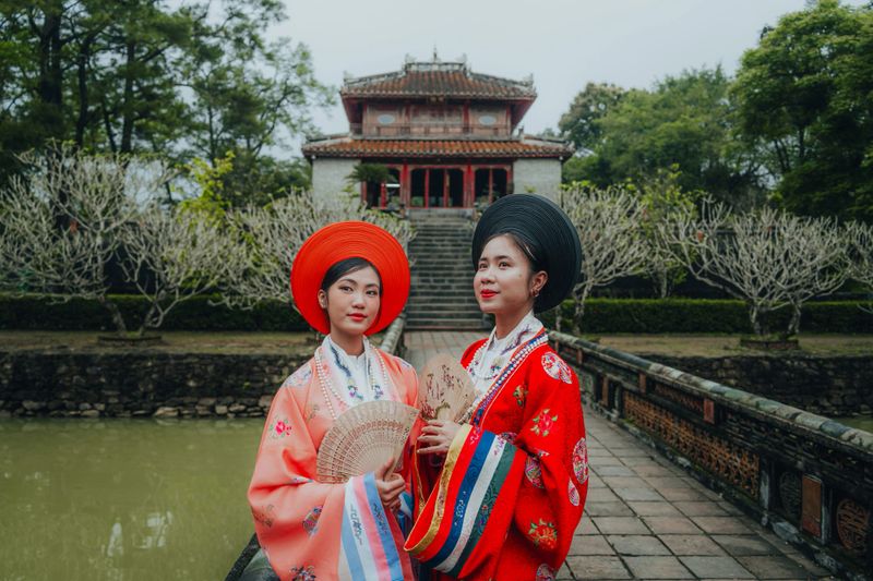 Two young Vietnamese woman wearing New Year celebration dress called Nhat Binh, this is the traditional costume of Vietnamese people in the Nguyen Dynasty in Minh Mang tomb, Hue city, Vietnam