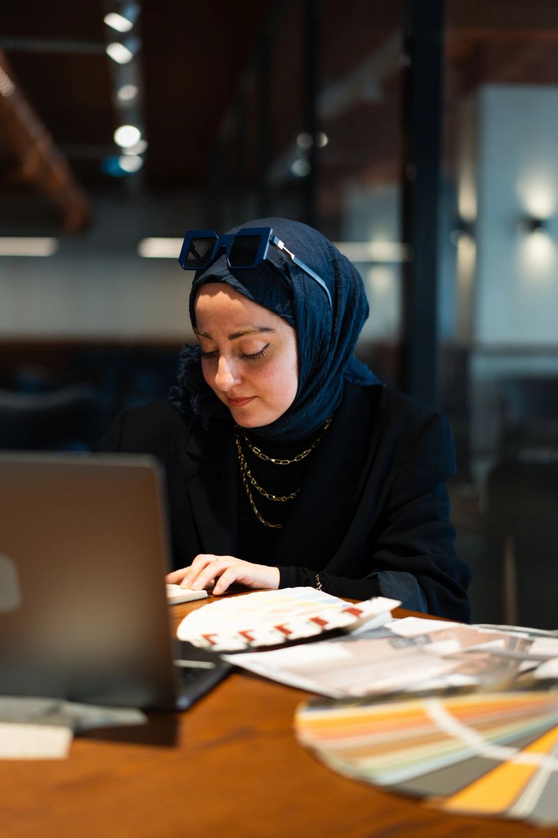 Muslim architect working at a modern cafe, choosing colors and designs for her next project
