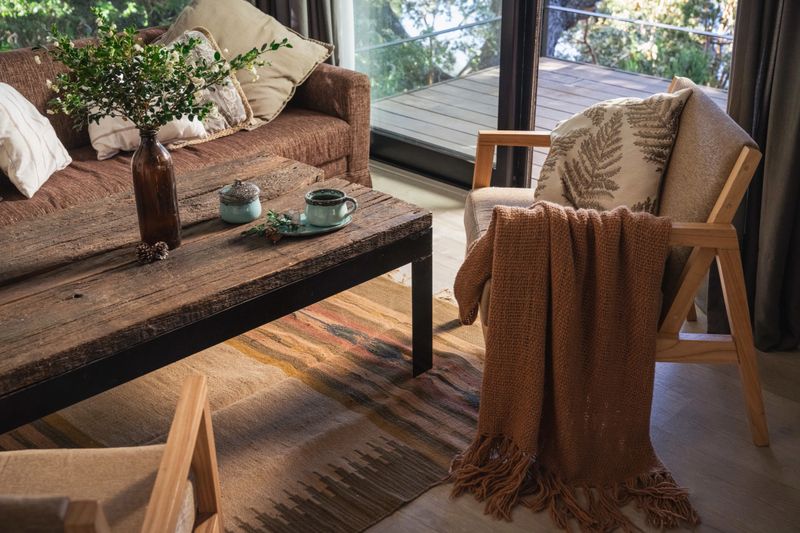 Rustic living room, with wooden decoration, earth colors, blankets, cup of coffee.