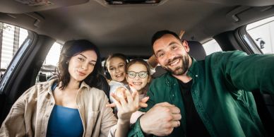 Happy family taking a selfie inside a car.