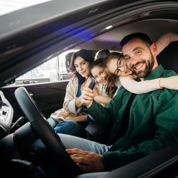 Happy family inside car holding key fob.