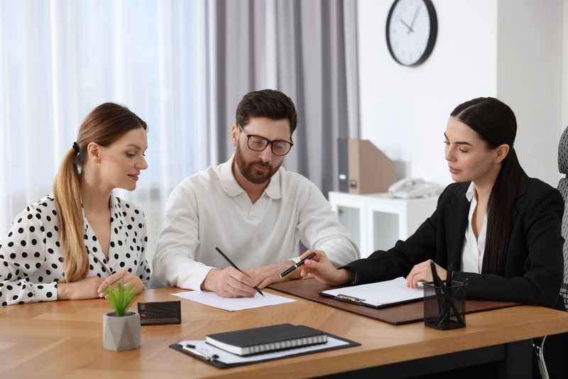 Couple signing document while having meeting with lawyer in office