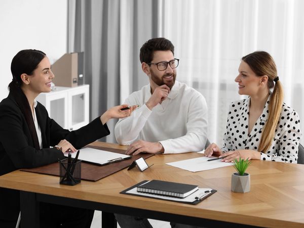 Three professionals having a friendly business discussion at a wooden table.