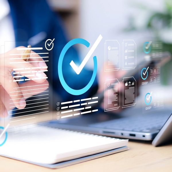 Person interacting with virtual checklists and documents over a laptop and notebook.