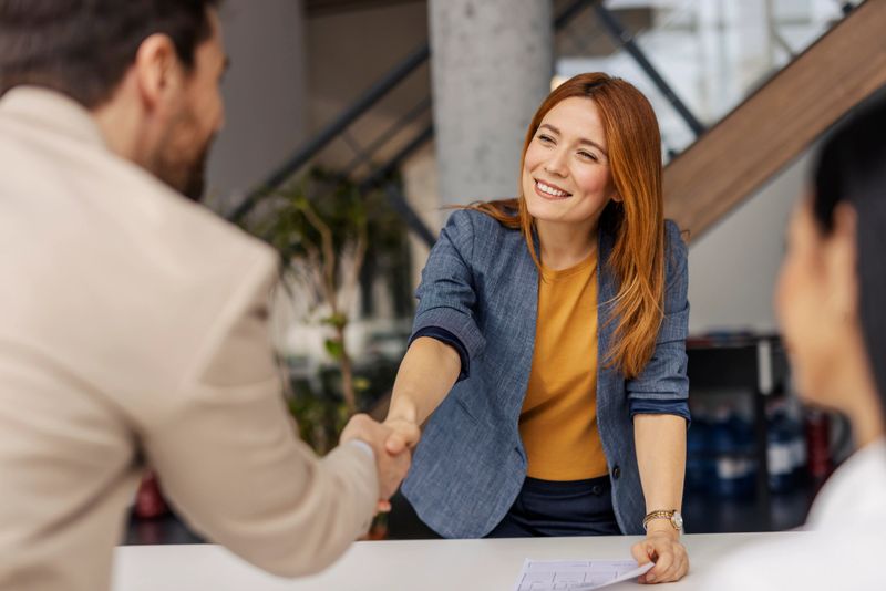 Portrait of friendly smiling female boss shaking hands with businessman on a briefing at corporate office.