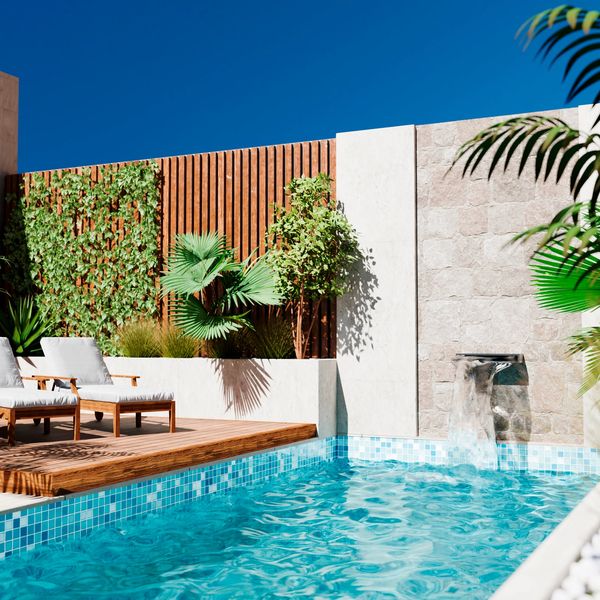 Modern outdoor pool with water feature and lounge chairs under bright blue sky.