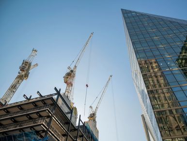 Construction cranes with modern glass building.