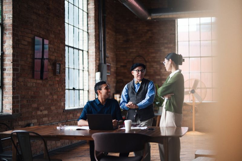 A diverse group of colleagues engaging in a discussion in a stylish office space. Capturing teamwork, productivity, and a modern workplace atmosphere.