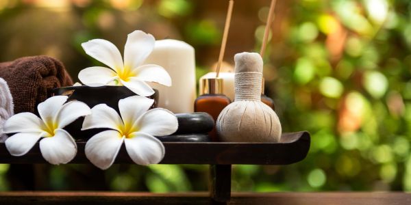 Spa setup with white flowers, candles, and massage tools.