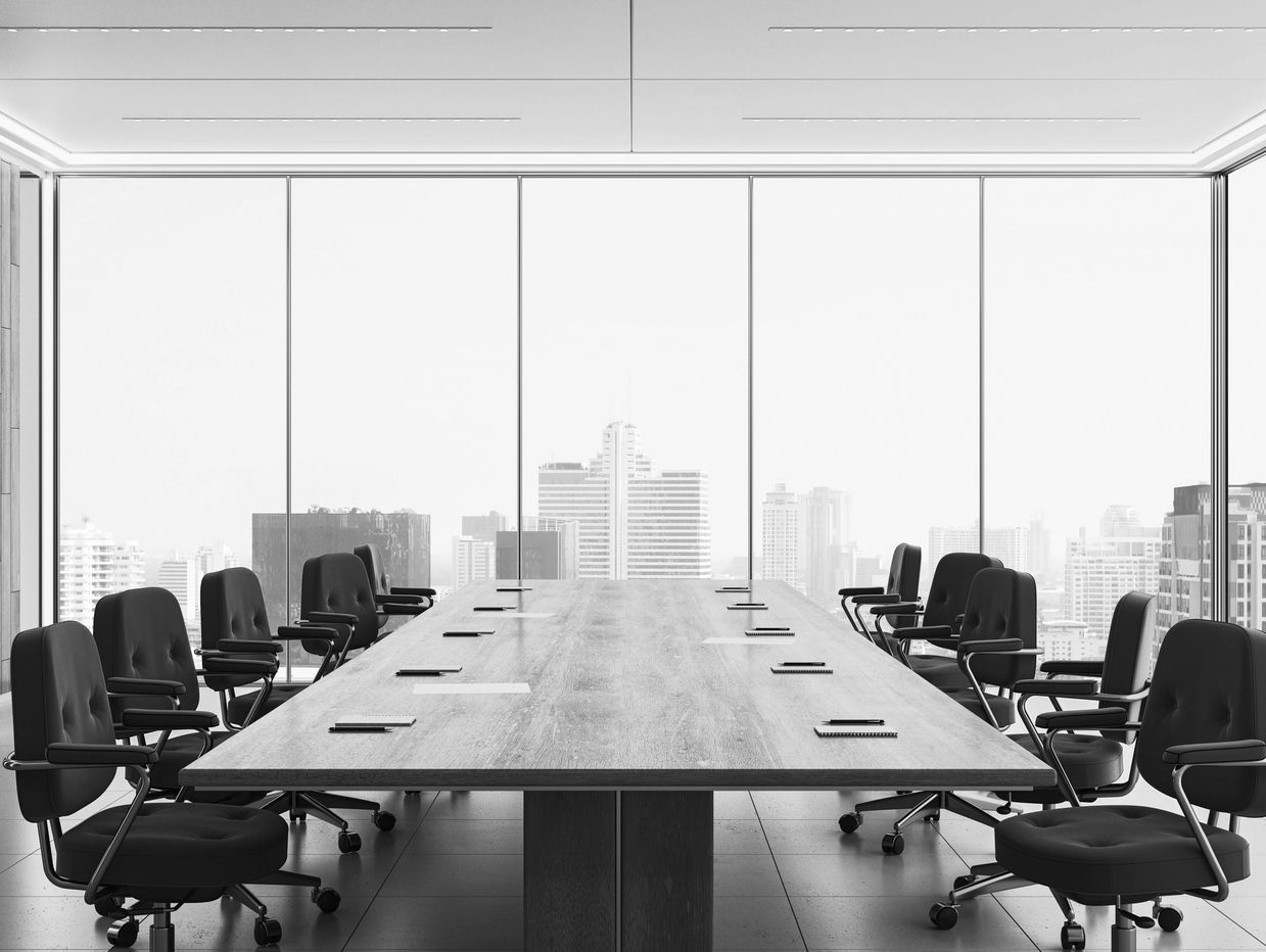 Modern empty conference room with a large table and city view through glass windows.