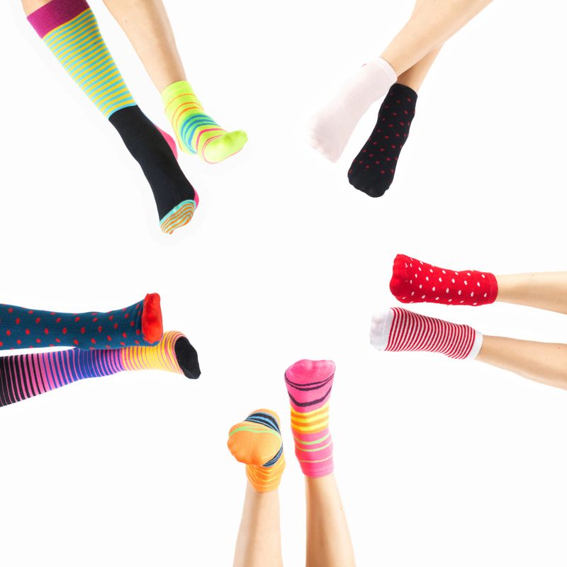 Down syndrome awareness, lost sock memorial day concept. Women legs with various colorful socks on feet in white background with copy space