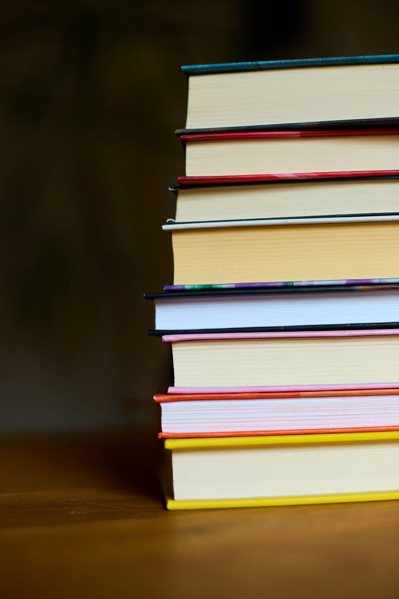 A collection of colorful books stacked neatly on a wooden table, evoking a sense of warmth and inviting readers to explore the stories within them.