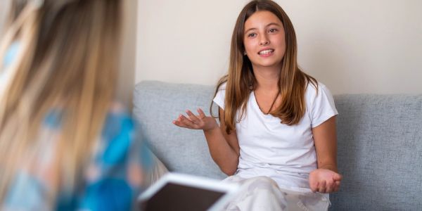 Teen girl talking during conversation on couch.