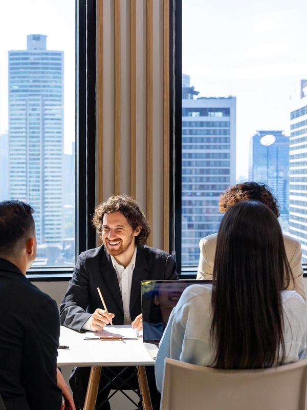 Diverse professionals engaged in a lively meeting in a modern office with city views.