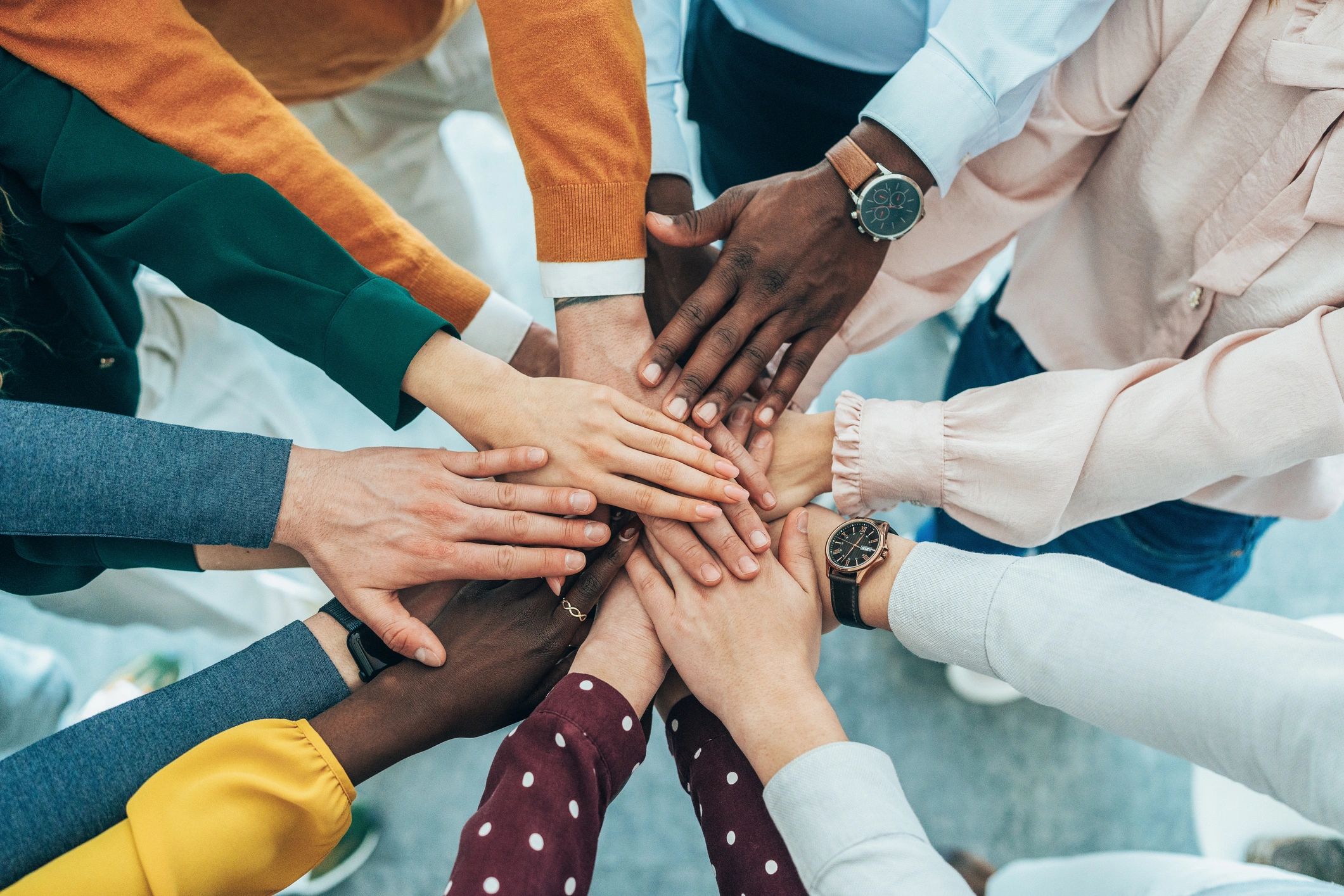 Diverse group stacking hands in unity and teamwork.