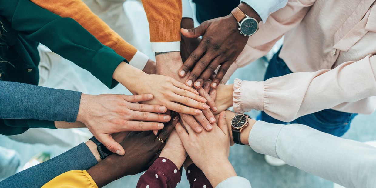 Diverse group of people stacking hands in a show of unity and teamwork.