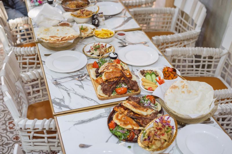 A beautifully arranged marble table in Dubai featuring Middle Eastern dishes like grilled meats, fresh salads, and flatbreads under soft natural light, creating a welcoming dining atmosphere.