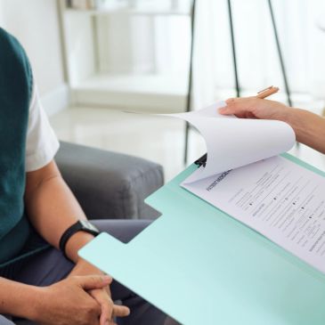 A person holding a clipboard with a questionnaire form during a consultation.