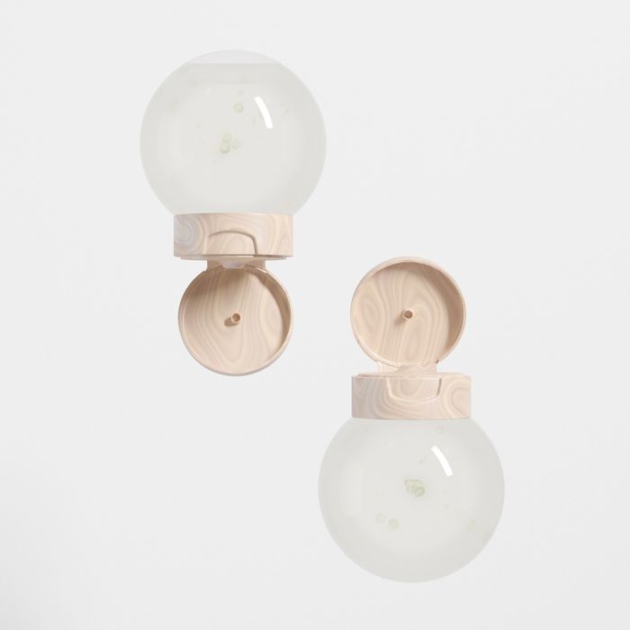 Two round cosmetic bottles with beige marbled flip-top caps.