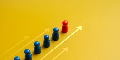 Red figure leading a line of blue figures with upward arrows on yellow background.