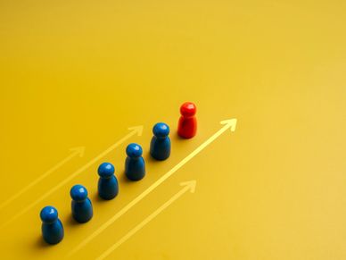 Red pawn leading a group of blue pawns on an upward arrow.