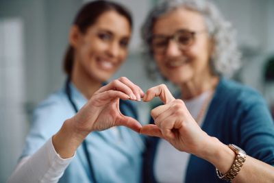 Two women making a heart shape with their hands.