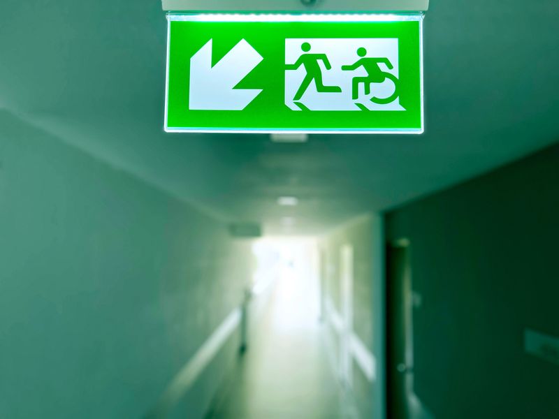 emergency exit sign, Emergency exit sign with wheelchair accessibility symbol in a modern building corridor. Safety evacuation route for people with disabilities