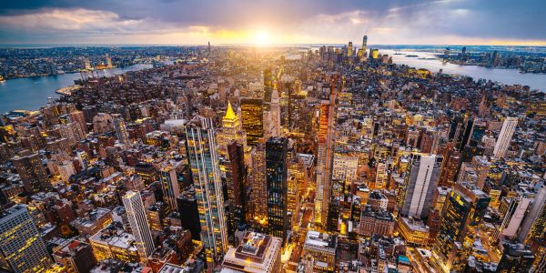 Sun setting over a bustling cityscape packed with buildings.