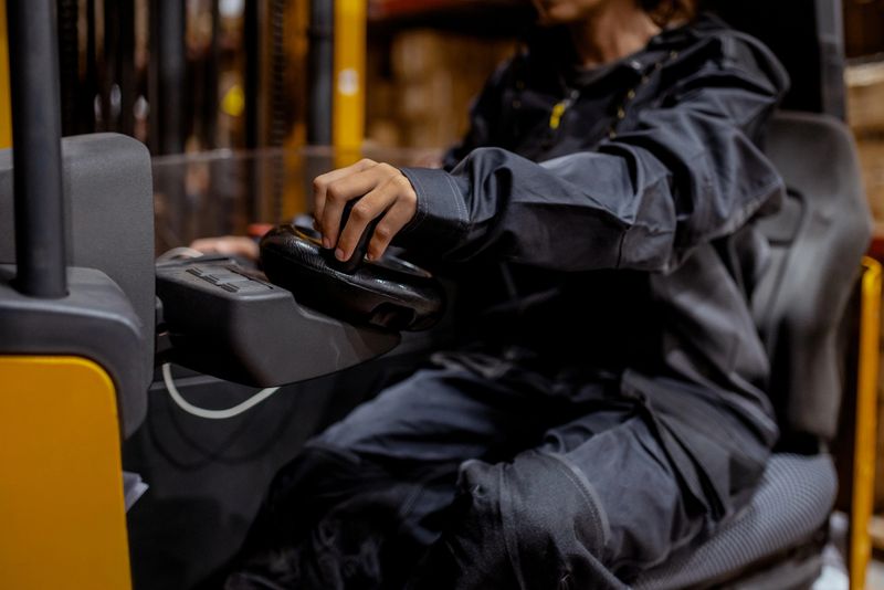The hands of an unrecognized worker grip the forklift controls, highlighting the daily labor behind seamless warehouse operations.