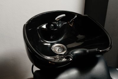 Black salon shampoo basin against a white wall.