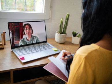 Woman taking notes during a video call on her laptop.