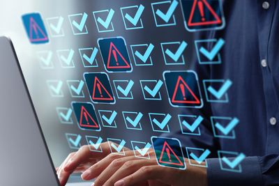 Security professional performing vulnerability assessment with checkmarks and warning alerts on scre