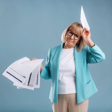Senior woman holds papers, looking tired and stressed.