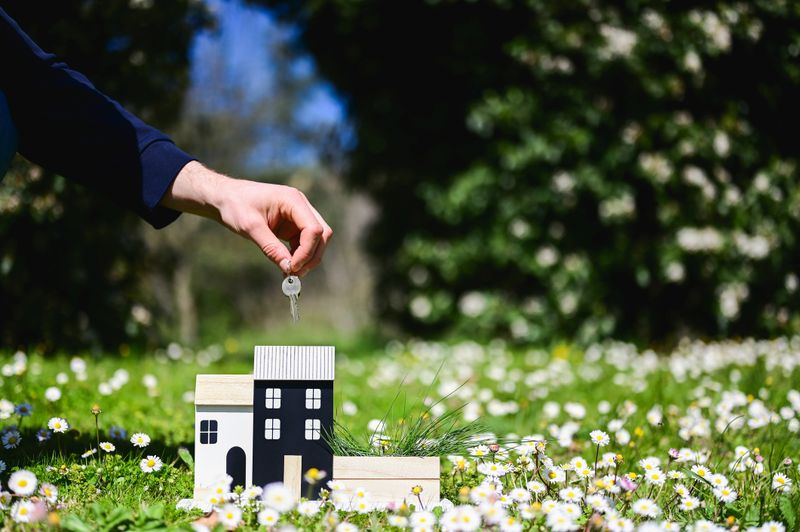 Real estate agent holding keys of new house in a field of daisies